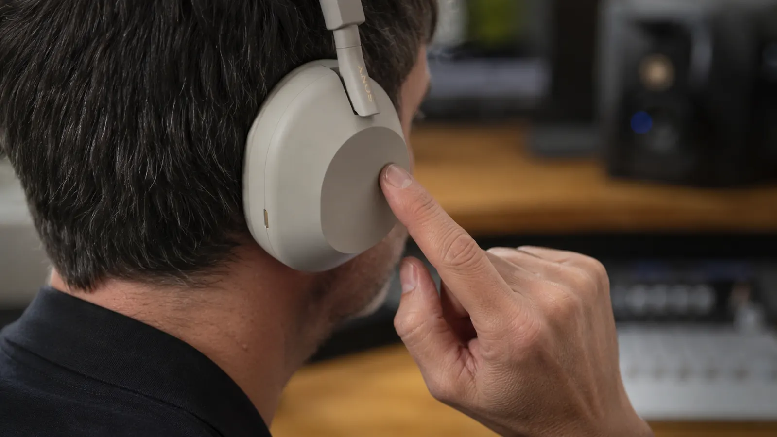 Close-up of the Sony WH-1000XM5 noise-cancelling microphone array and earcup controls being used by a professional